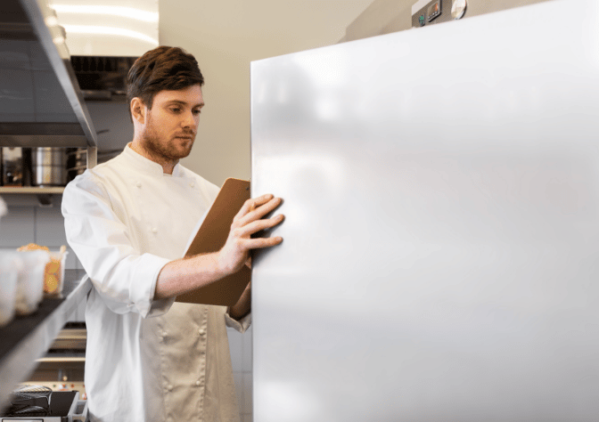 chef wasting commercial kitchen energy by keeping fridge door open